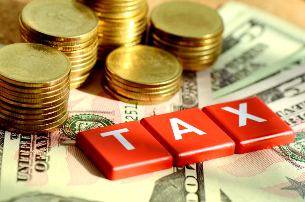 A pile of money and the word "tax" written on red tiles.