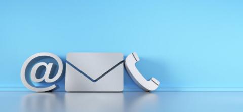 Communication symbols for phone, e-mail and letter standing on the floor against a wall