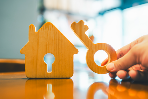 illustration of hand holding a wooden key next to a toy house